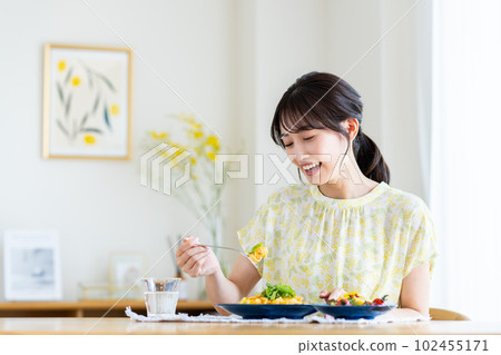 Young woman eating pasta at home 102455171