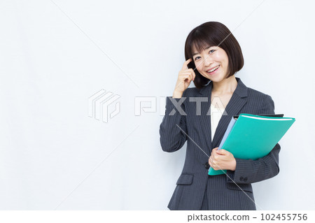 A woman in her thirties in a suit thinking with a smile in front of a white background A woman in her thirties in a suit thinking with a smile in front of a white background 102455756