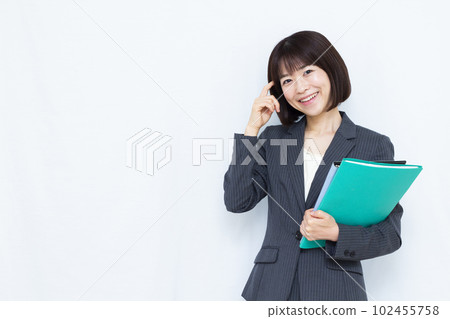 A woman in her thirties in a suit thinking with a smile in front of a white background A woman in her thirties in a suit thinking with a smile in front of a white background 102455758