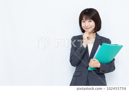 A woman in her thirties in a suit thinking with a smile in front of a white background A woman in her thirties in a suit thinking with a smile in front of a white background 102455759