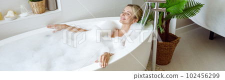 View from above on young beautiful female lying in warm bath, smiling and resting in spa. 102456299