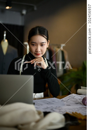 A female fashion designer using laptop, planning and working on her new collection 102456937