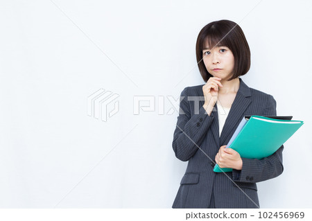 A woman in her thirties in a suit who is worried in front of a white background 102456969