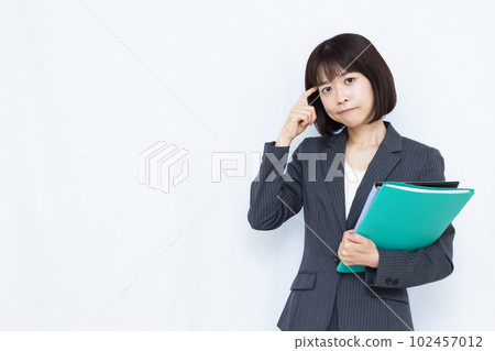 A woman in her thirties in a suit who is worried about holding her head in front of a white background 102457012