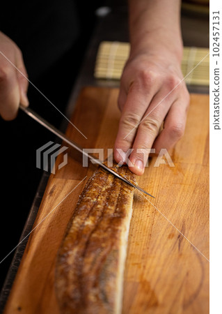 Chef slicing eel for japanese sushi rolls cooking 102457131