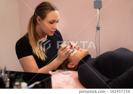 Specialist Using Tweezers During Eyelash Extension Treatment 102457159