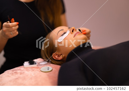 Woman Going Through Eyelash Extension Treatment At Beauty Clinic Woman Going Through Eyelash Extension Treatment At Beauty Clinic 102457162