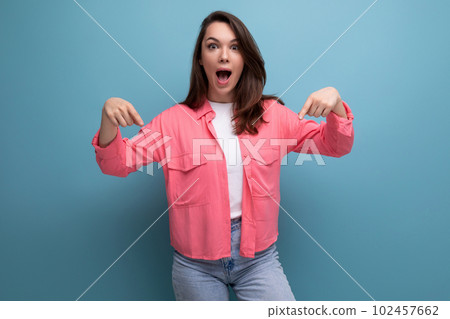 cheerful brunette lady in a pink shirt and jeans points her finger at the infomation on a studio 102457662