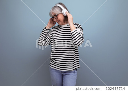 stylish modern 60s old lady listens to music in headphones and dances on a bright background with 102457714
