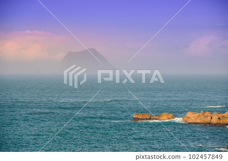 A small island shrouded in mist, blue sea and blue sky. 102457849