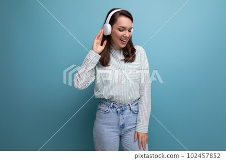energetic pretty cute brunette young woman in shirt listening to music on studio background with 102457852