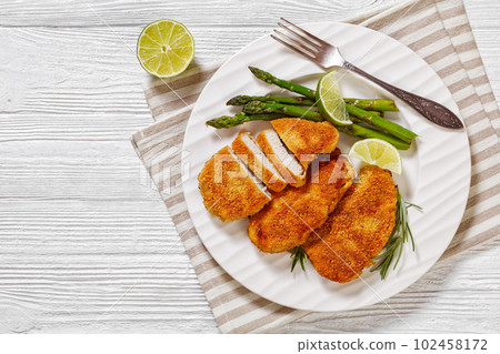 breaded chicken breasts with asparagus and lime 102458172