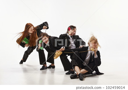 Portrait with businesswomen wearing black costume holding phone receiver and screaming over white color studio background. Female competition 102459014