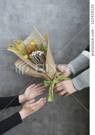 Man and woman handing a bouquet of dried flowers 102459320