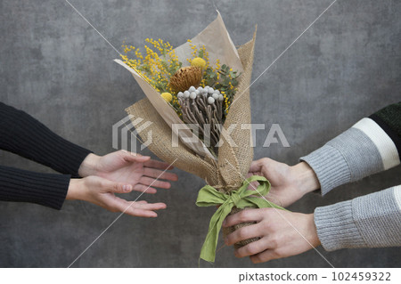 Man and woman handing a bouquet of dried flowers 102459322