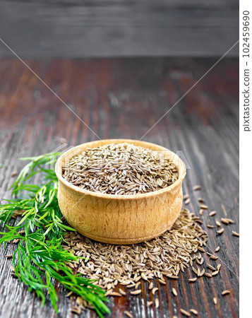 Cumin seeds in bowl with herbs on wooden board Cumin seeds in bowl with herbs on wooden board 102459690