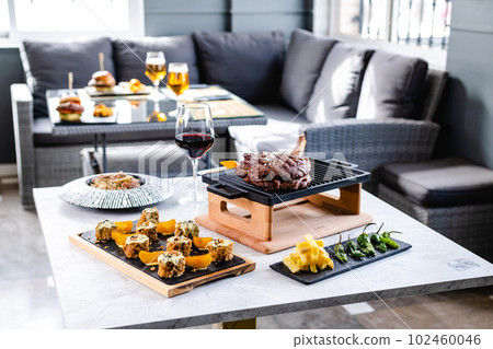 Several dishes served in a restaurant ready to eat. Steak Tomahawk, risotto, potatoes and peppers 102460046