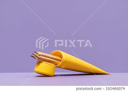 Yellow pencil case with pencils on lilac violet background. stationery with copy space for back to school or education and craft concept. Bright Yellow minimal. Neon acid colors 102460074