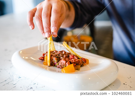 Crop person serving steak tartare 102460081