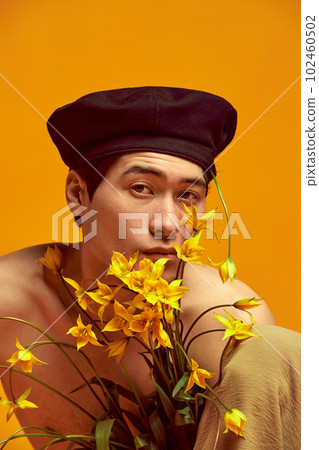 Portrait of young guy posing shirtless in black beret against yellow studio background. Stylish spring summer collection 102460502