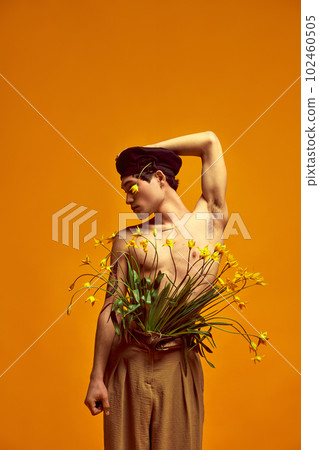 Blooming style. Portrait of attractive young male, model posing in black beret and beige classical trousers against yellow studio background Blooming style. Portrait of attractive young male, model posing in black beret and beige classical trousers against yellow studio background 102460505
