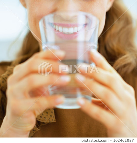 Closeup on young housewife drinking water 102461087