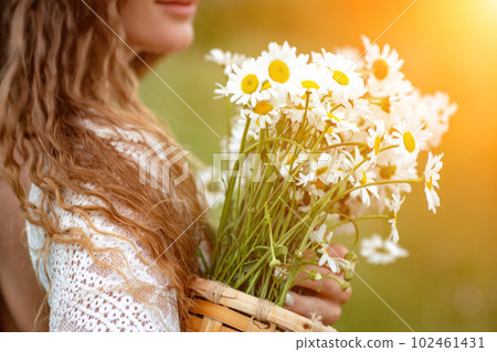 A middle-aged woman holds a large bouquet of daisies in her hands. Wildflowers for congratulations A middle-aged woman holds a large bouquet of daisies in her hands. Wildflowers for congratulations 102461431