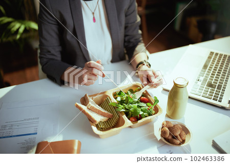 Modern female worker in green office eating salad 102463386