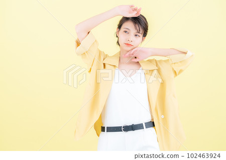 年輕女子穿著時髦的衣服在黃色背景下擺姿勢 102463924