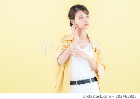 年輕女子穿著時髦的衣服在黃色背景下擺姿勢 102463925