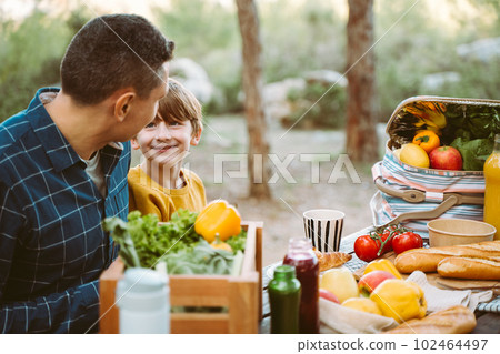 Father hugs his school boy son on a family picnic in mountains forest park. Child kid and his dad taking a rest and enjoying a picnic while hiking in the mountains 102464497