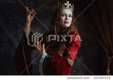 medieval queen in red dress with white makeup and crown 102464559