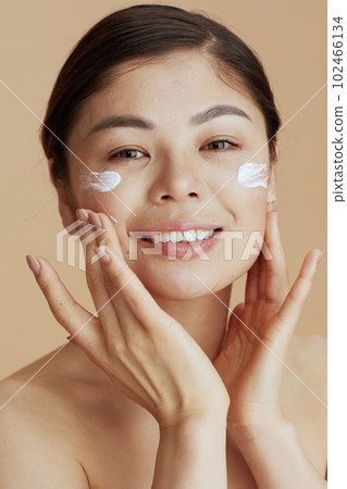 Portrait of modern woman with facial cream on face 102466134