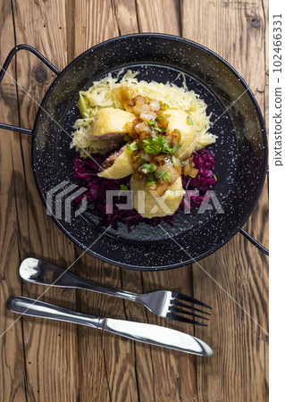 dumpllings filled with smoked meat served with red and white cabbage 102466331