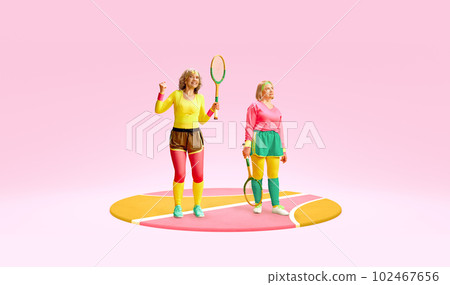 Two senior women in colorful, comfortable sportswear posing with retro tennis rackets over pink background. Winner Two senior women in colorful, comfortable sportswear posing with retro tennis rackets over pink background. Winner 102467656