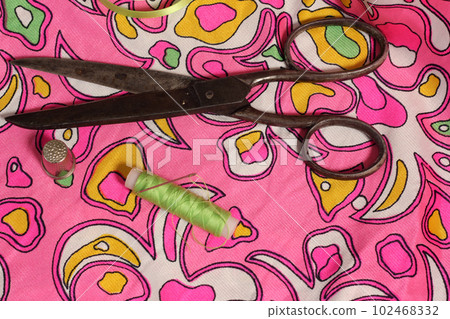 Spool of Green Thread, Thimble and Needle on Retro Pink and Green Fabric 102468332