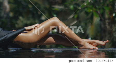 Long Tanned Legs of Young Woman Relaxing at Infinity Pool in Luxury Bikini Long Tanned Legs of Young Woman Relaxing at Infinity Pool in Luxury Bikini 102469147