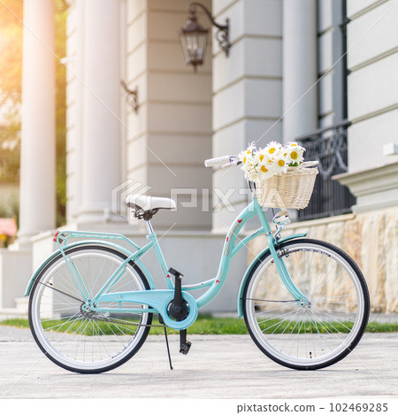Bike at the summer sunset on the tiled road in the city park. Cycle closeup wheel on blurred summer background. Cycling down the street to work at summer sunset. Bicycle and ecology lifestyle concept. Bike at the summer sunset on the tiled road in the city park. Cycle closeup wheel on blurred summer background. Cycling down the street to work at summer sunset. Bicycle and ecology lifestyle concept. 102469285