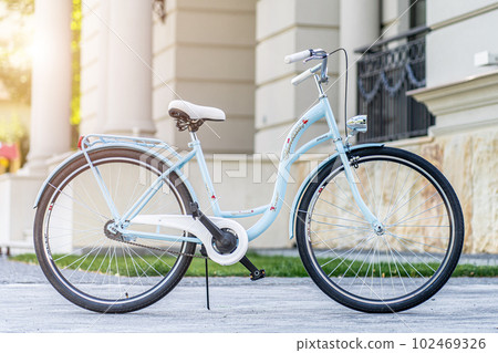 Side view of a modern city urban city bike or bicycle for street road. City bicycle parked on a lawn. Urban bike standing upright on grass, static, no people. Side view of a modern city urban city bike or bicycle for street road. City bicycle parked on a lawn. Urban bike standing upright on grass, static, no people. 102469326
