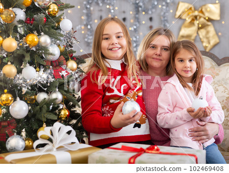 Mom with two daughters hugging in Christmas interior Mom with two daughters hugging in Christmas interior 102469408