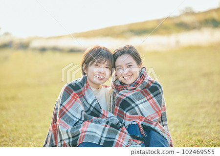 一個年輕女人和她的朋友一起裹一條毯子 102469555
