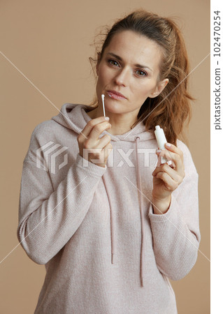 woman applying ointment using cotton swab isolated on beige 102470254