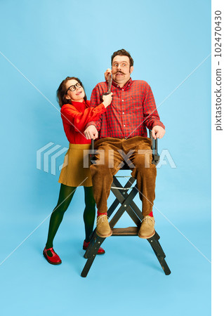 Portrait with scared man and crazy woman, barber doing new haircut, moustache over blue color studio background. Male barbershop 102470430