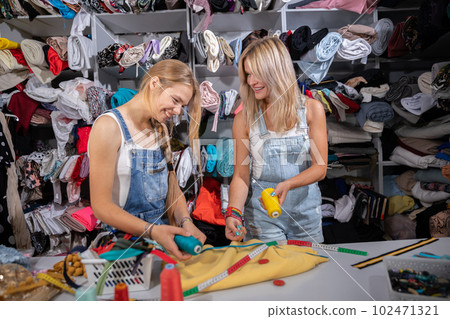 Both girls choose the right color of thread for the yellow fabric. 102471321