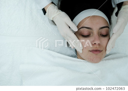 Cosmetologist cleaning woman's face before applying face treatments  102472063