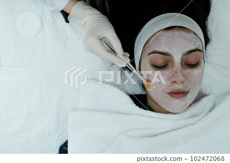 Top view of woman having a calming cosmetic mask applied on her face  102472068