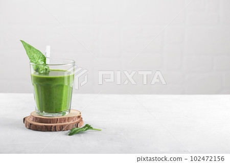 Healthy green smoothie with spinach, banana, and vegan milk in glass on light grey background, copy space 102472156