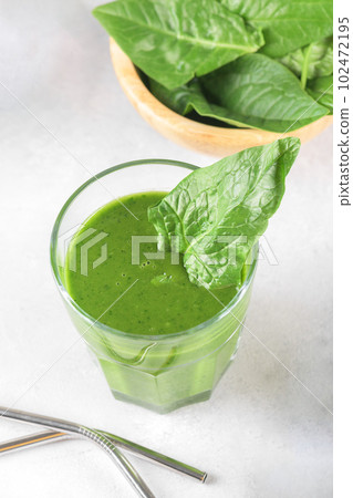 Healthy green smoothie with spinach, avocado, banana, and vegan milk in glass and fresh ingredients, top view 102472195