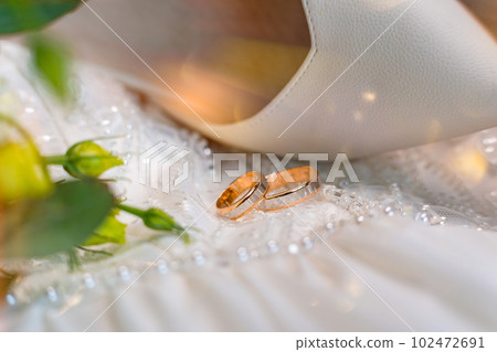 Two gold wedding rings and shoes on a beaded dress. Jewelry for bride and groom. Two gold wedding rings and shoes on a beaded dress. Jewelry for bride and groom. 102472691
