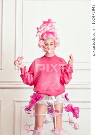 Portrait of charming girl, princess wearing pink wig and eating sweet cotton over luxury interior background. Sugar diet Portrait of charming girl, princess wearing pink wig and eating sweet cotton over luxury interior background. Sugar diet 102472942